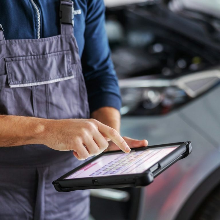 Mechaniker verwendet ein Tablet zur Fahrzeugdiagnose in einer Werkstatt.