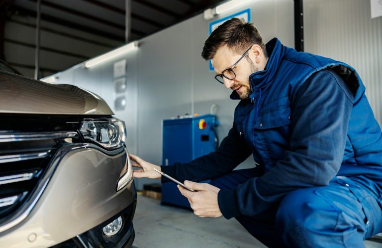 Ein Techniker überprüft die Front eines Fahrzeugs in einer Werkstatt.